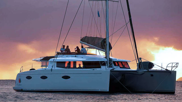Bareboat sailing catamaran at tropical sunset